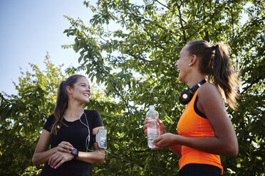 Two young female runners chatting in park - CUF29370