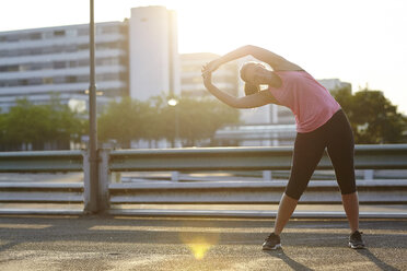 Young female runner warming up on rooftop - CUF29385