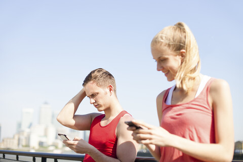 Läufer benutzen Smartphone auf Brücke, lizenzfreies Stockfoto