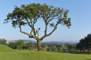 Golfer standing in tree preparing to take golf swing - CUF29423