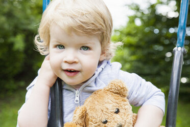 Portrait of female toddler playing on park swing - CUF29443