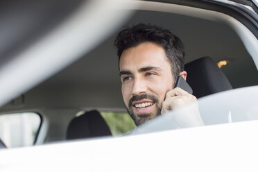 Junger Geschäftsmann spricht im Auto mit seinem Smartphone - CUF29449