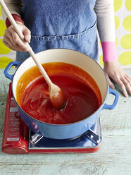 Frau bei der Zubereitung von Tomatenketchup Rezept Schritt 3, Rühren von pürierten Tomaten - CUF29481