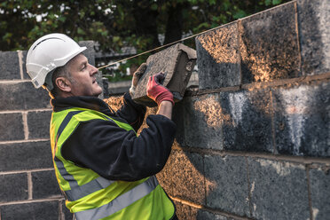 Arbeiter legen Ziegelsteine auf der Baustelle - CUF29486