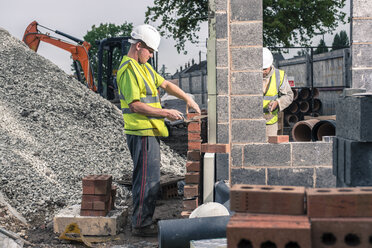 Arbeiter legen Ziegelsteine auf der Baustelle - CUF29489