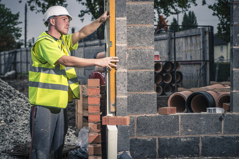 Arbeiter legen Ziegelsteine auf der Baustelle - CUF29490