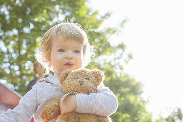 Portrait of cute female toddler hugging teddy bear on playground slide - CUF29506