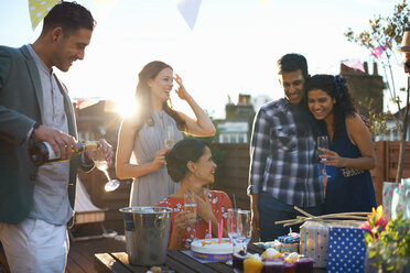 Freunde auf einer Party auf der Dachterrasse schenken Champagner ein - CUF29563