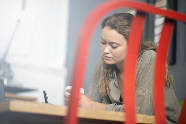 Druckdesignerin bei der Arbeit am Schreibtisch in der Werkstatt - CUF29570