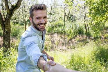 Young man holding hand looking at camera smiling - CUF29667