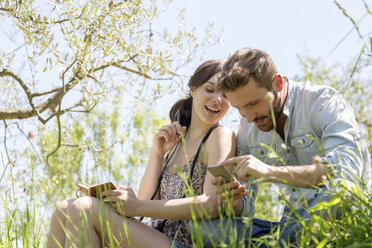 Niedriger Blickwinkel auf ein junges Paar, das lächelnd auf sein Smartphone schaut - CUF29673