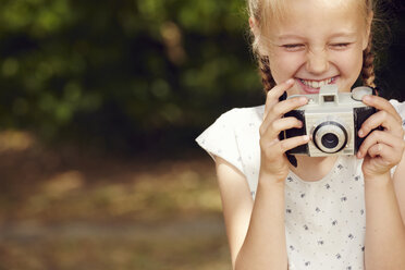 Cropped view of girl holding film camera eyes closed smiling - CUF29689