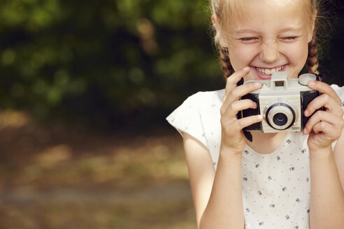 Abgeschnittene Ansicht eines Mädchens, das eine Filmkamera hält und lächelnd die Augen schließt - CUF29689