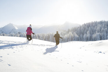 Rückansicht eines älteren Paares mit Wanderstöcken in einer verschneiten Landschaft, Sattelbergalm, Tirol, Österreich - CUF29698