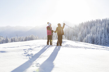 Senior couple on snow covered landscape holding walking poles looking away, Sattelbergalm, Tyrol, Austria - CUF29699