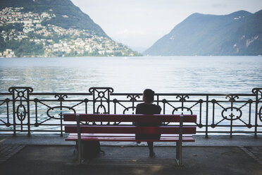 Rückansicht einer silhouettierten Frau auf einer Parkbank mit Blick auf den Luganer See, Schweiz - CUF29746