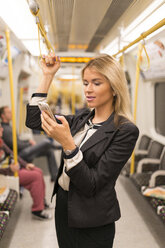 Businesswoman texting on tube, London Underground, UK - CUF29748