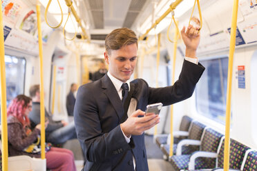 Businessman texting on tube, London Underground, UK - CUF29750