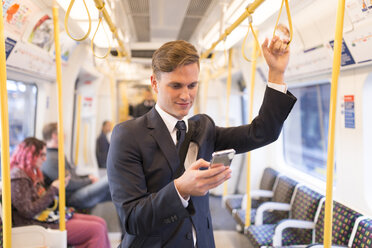 Geschäftsmann schreibt eine SMS in der U-Bahn, London Underground, UK - CUF29750