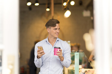 Man with takeaway coffee using smartphone - CUF29756