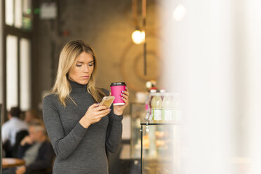 Frau mit Kaffee zum Mitnehmen und Smartphone - CUF29757