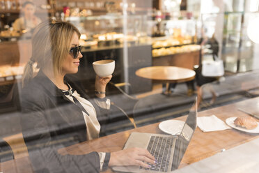 Geschäftsfrau arbeitet an einem Laptop in einem Café - CUF29763