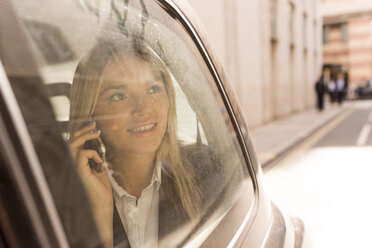 Geschäftsfrau schaut aus einem schwarzen Taxi, London, UK - CUF29769