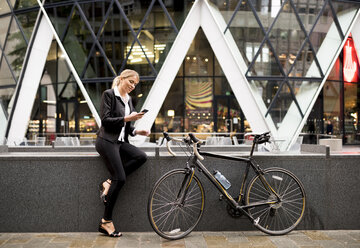 Businesswoman with bike outside 30 St Mary Axe, London, UK - CUF29777