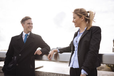 Businessman and businesswoman leaning on rail - CUF29780