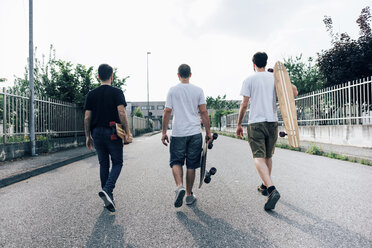 Rückansicht von jungen Männern, die mit Skateboards auf einem Weg laufen - CUF29787