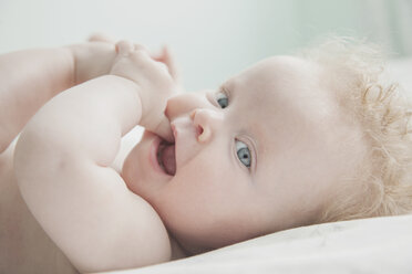 Baby girl lying down, fingers in mouth - CUF29805