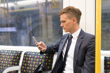 Geschäftsmann schreibt eine SMS in der U-Bahn, London Underground, UK - CUF29812