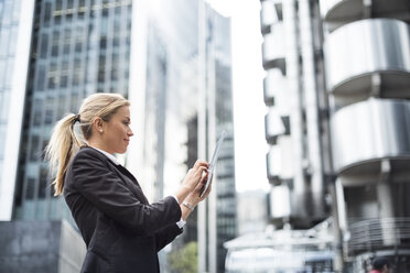 Businesswoman using digital tablet in street, London, UK - CUF29814