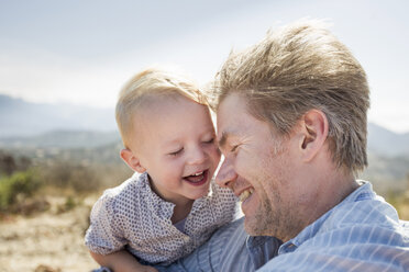 Mature man and toddler daughter laughing, Calvi, Corsica, France - CUF29831