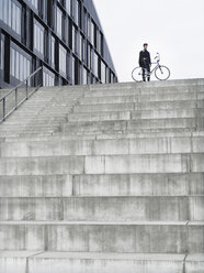 Urban cyclist with bicycle standing on top of stairway - CUF29974