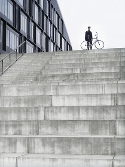 Stadtradler mit Fahrrad auf einer Treppe stehend - CUF29974