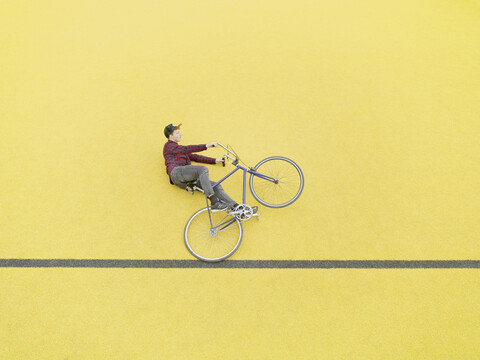 Urbaner Radfahrer, der gegen eine gelbe Wand strampelt, lizenzfreies Stockfoto