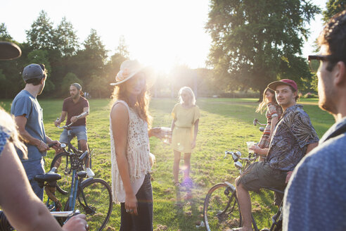 Gruppe von Erwachsenen, die bei Sonnenuntergang auf Fahrrädern im Park ankommen - CUF29999