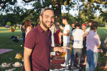 Porträt eines jungen Mannes auf einer überfüllten Party im Park bei Sonnenuntergang - CUF30006