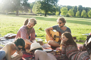 Group of friends relaxing on rug at sunset park party - CUF30029