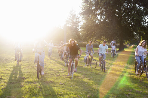 Scharen erwachsener Freunde, die auf Fahrrädern zur Party im Park bei Sonnenuntergang ankommen - CUF30034
