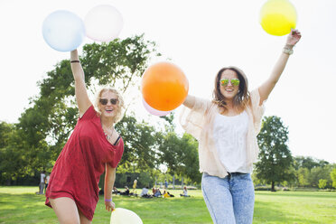 Porträt von zwei jungen Frauen, die mit Luftballons auf einer Parkparty tanzen - CUF30045