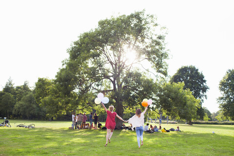 Rückansicht von zwei jungen Frauen, die mit Luftballons auf einer Parkparty tanzen, lizenzfreies Stockfoto