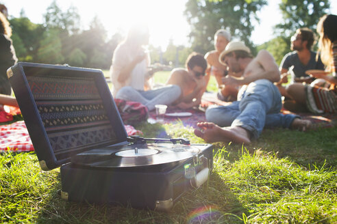 Erwachsene Freunde, die sich bei Sonnenuntergang im Park entspannen und einer Schallplatte lauschen - CUF30066