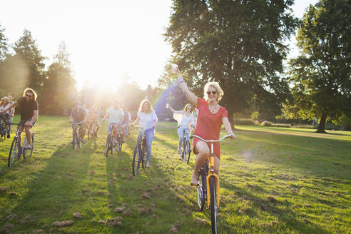 Gruppe feierfreudiger Erwachsener, die auf Fahrrädern zur Sonnenuntergangs-Parkparty ankommen - CUF30074