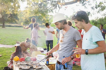 Young men barbecuing at group party in park - CUF30078