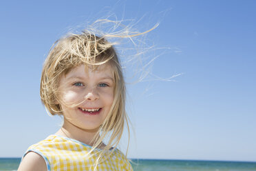 Portrait of girl with blond flyaway hair on beach - CUF30106
