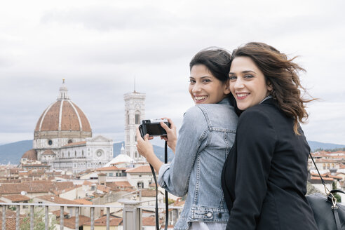 Lesbisches Paar, das den Dom von Florenz und Giottos Campanile fotografiert und dabei lächelnd über die Schulter schaut, Florenz, Toskana, Italien - CUF30161