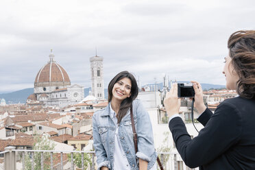 Junge Frau, die für einen Freund posiert, der ein Foto vor der Kathedrale von Florenz und dem Campanile von Giotto schießt, lächelnd über die Schulter, Florenz, Toskana, Italien - CUF30162