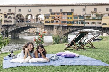 Lesbisches Paar auf einer Decke liegend vor der Ponte Vecchio über dem Fluss Arno, Florenz, Toskana, Italien - CUF30166